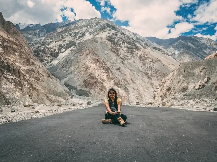 A traveller sitting in the middle of an empty mountain road