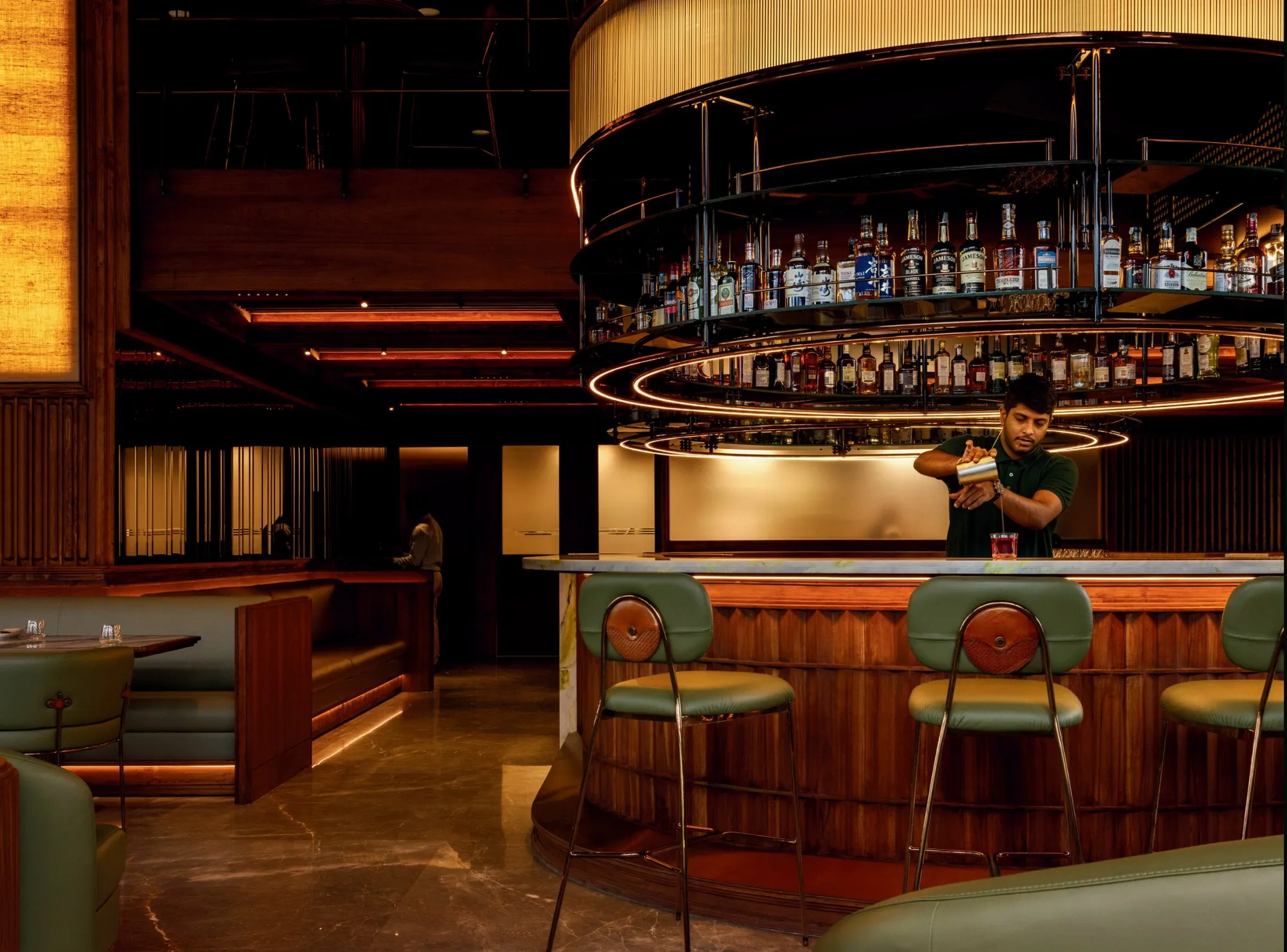 The circular bar at Muro, lit amber, a bartender at work